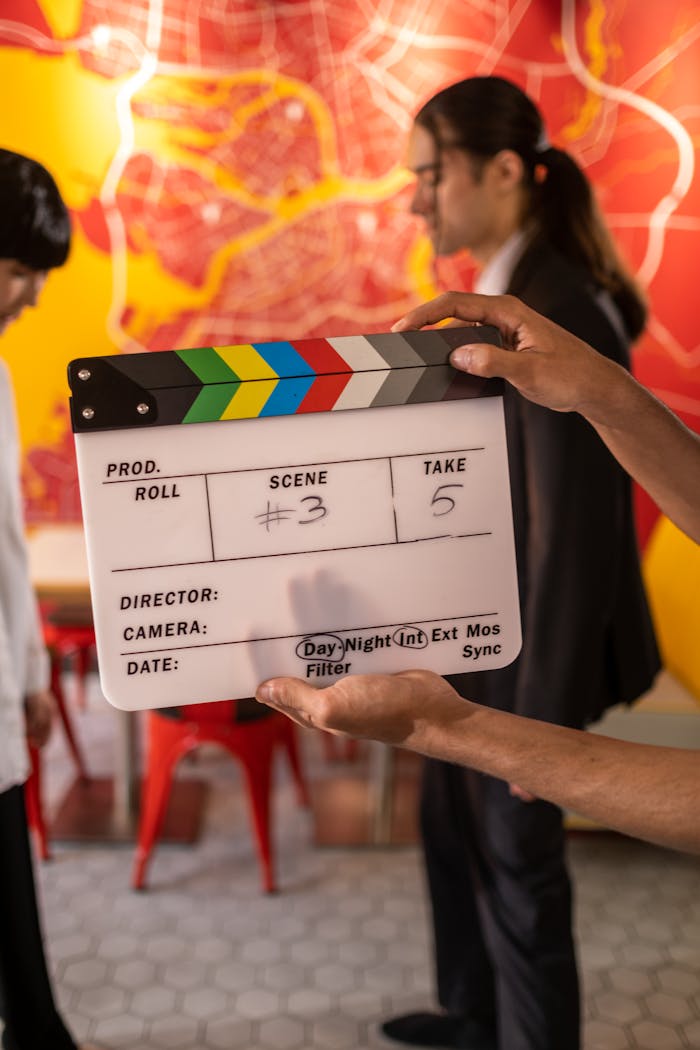 Behind-the-scenes image of a film set with a clapperboard and crew members.